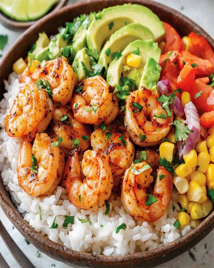 a bowl filled with shrimp and rice next to corn, avocado and tomatoes