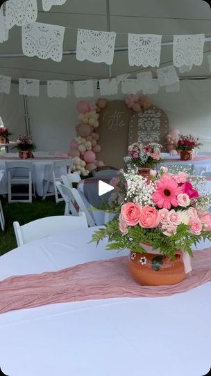 a vase filled with pink flowers sitting on top of a white table covered in lace