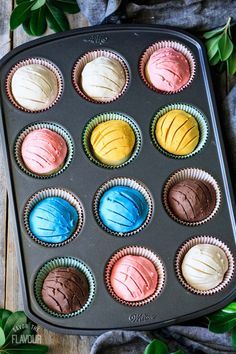 a muffin tin filled with different colored cupcakes