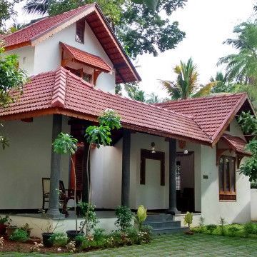 a white house with red tiled roof and trees