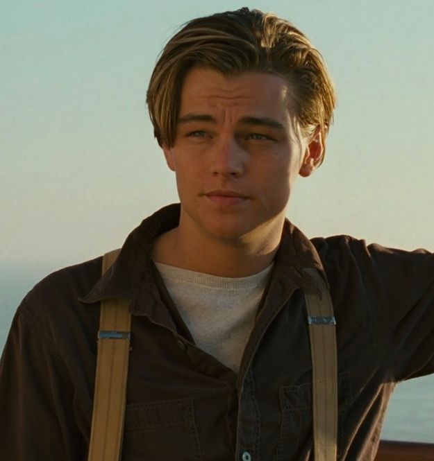 a young man with suspenders is looking at the camera while holding his hand on his shoulder