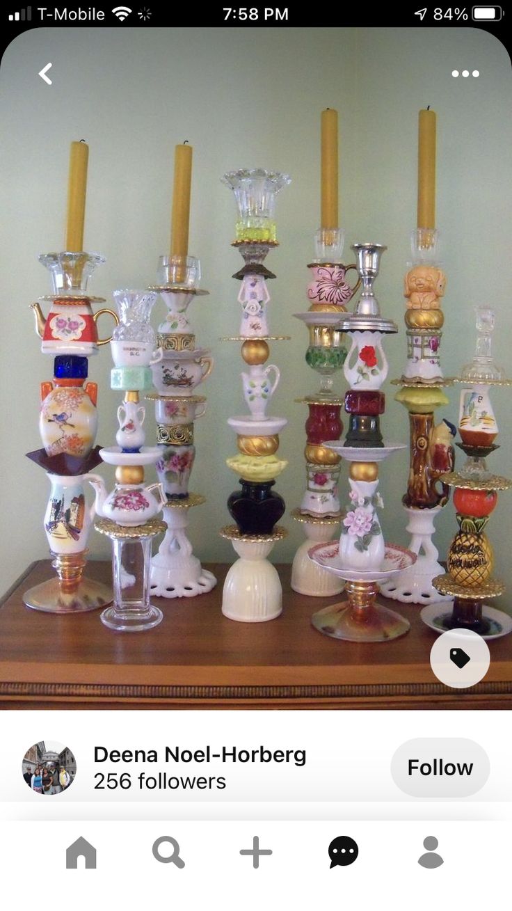 a collection of glass vases and candles on a wooden table in front of a wall