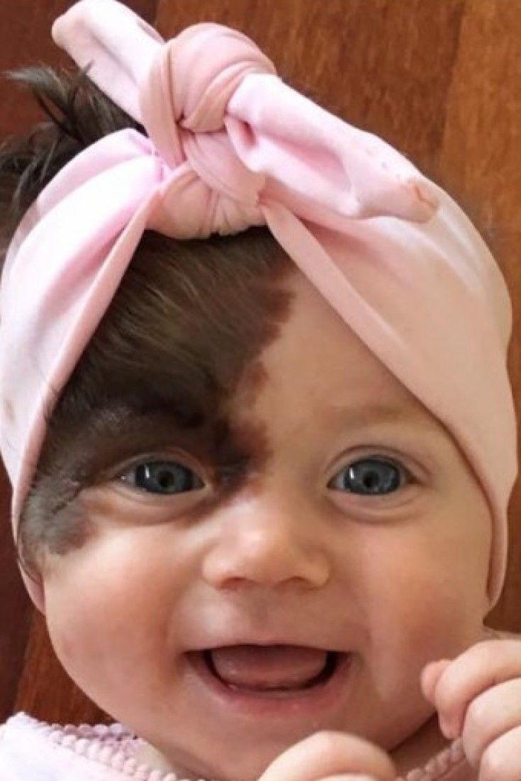 a smiling baby with a pink bow on her head