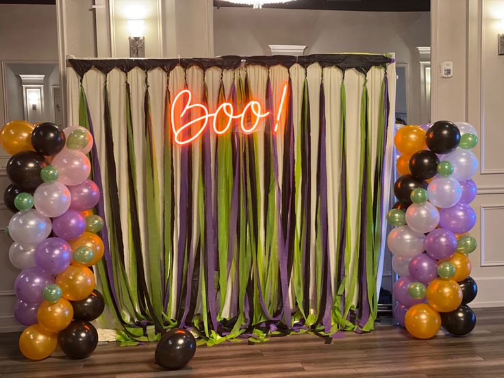 balloons and streamers are set up in front of a backdrop with the word boo on it