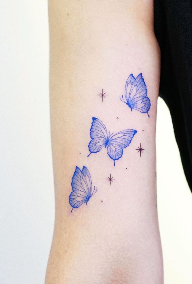 three blue butterflies on the left side of the arm, with stars in the background