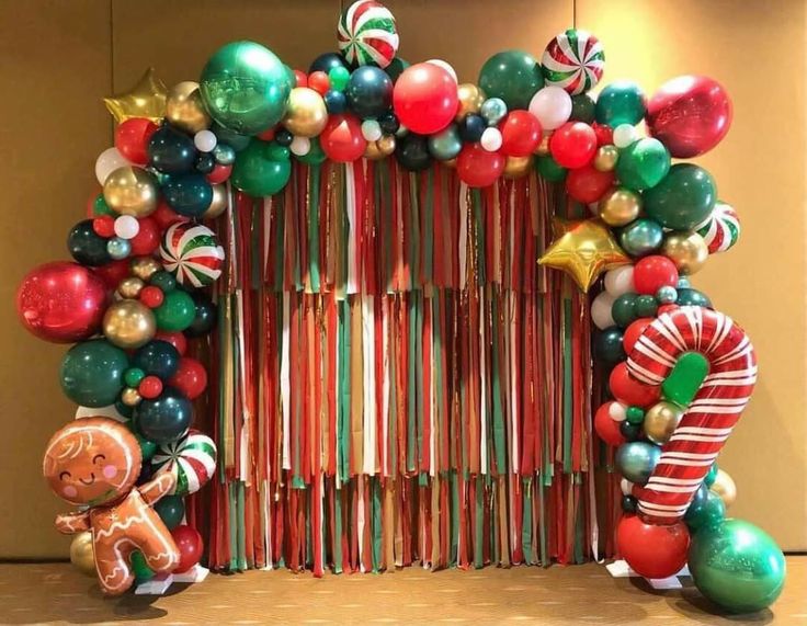 an arch made out of candy canes, balloons and candies with a gingerbread man standing next to it