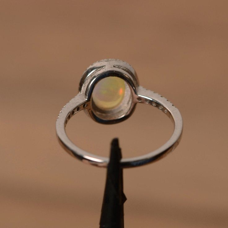 It is a natural opal ring. The main stone is 7mm*9mm oval white opal. The basic metal is sterling silver and plated with rhodium. To change the metal to a solid gold (white/rose) or platinum is also available, please ask for a quotation if you want. You can also go to my shop Home for more elegant rings: https://www.etsy.com/shop/godjewelry?ref=hdr_shop_menu Opal is the birthstone of October, it will be a great gift for your lover! Customization is always welcome and please feel free to contact Ethiopian Opal Oval Ring For Wedding, Fine Jewelry Opal Ring Oval Cabochon Birthstone, Oval Opal Jewelry With Bezel Setting, Oval Opal Rings With Bezel Setting, Elegant Silver Opal Ring With Halo Design, Fine Jewelry Opal Oval Cabochon Ring, Oval Opal Rings With Polished Finish, Oval Ethiopian Opal Birthstone Ring, Elegant Ethiopian Opal Ring With Oval Cabochon