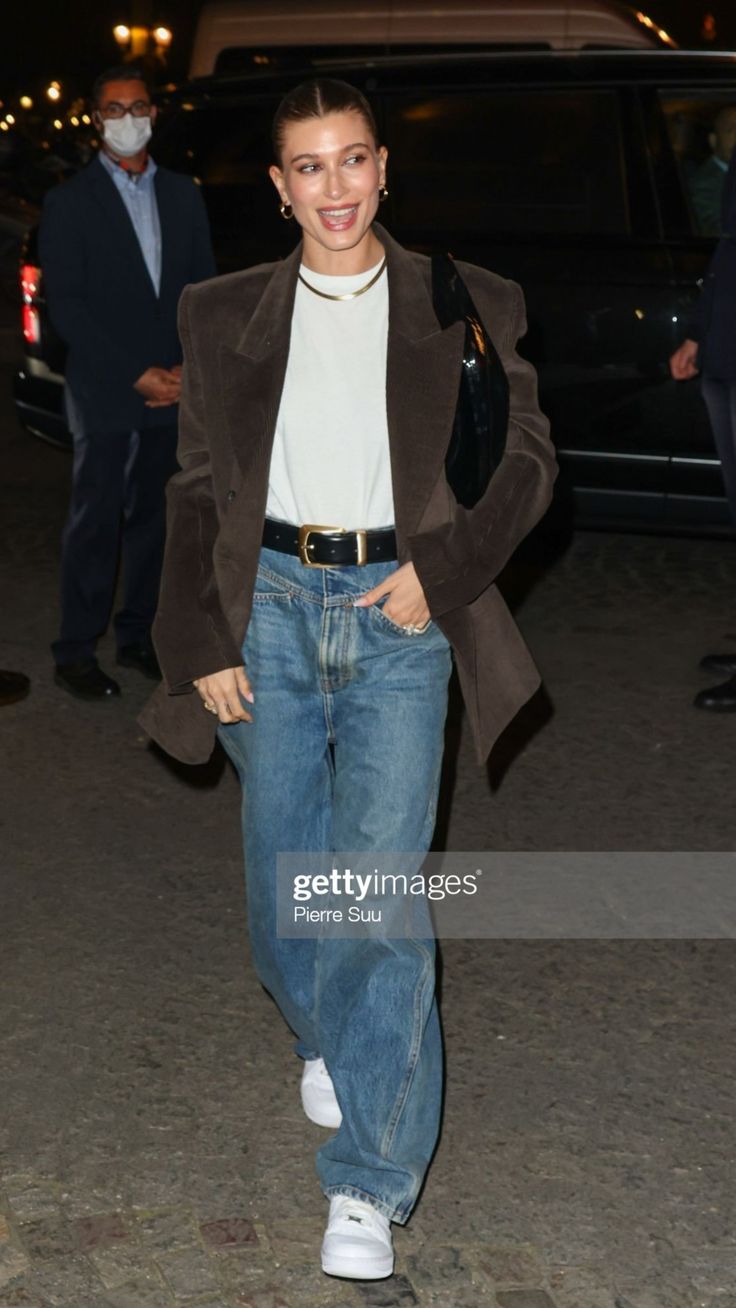 a woman in jeans and jacket walking down the street