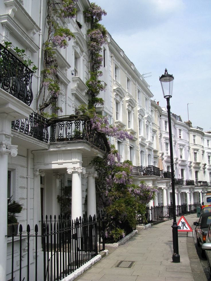 a row of white townhouses with flowers on the balconies