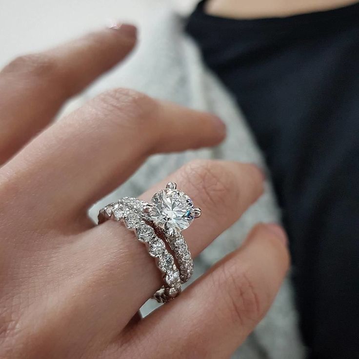 a woman's hand with a diamond ring on top of her finger and an engagement band