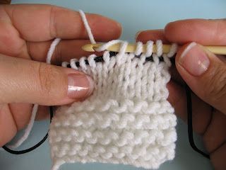 two hands are working on a white knitted object