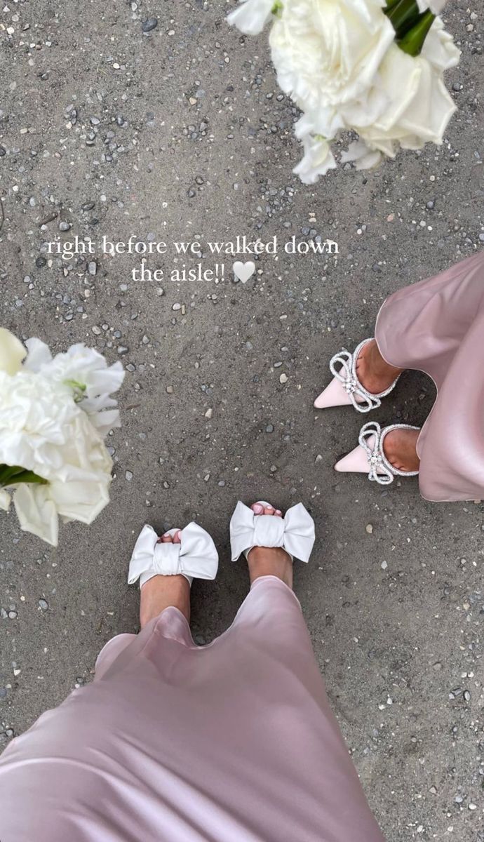 two women in wedding shoes standing next to each other with white flowers on the ground