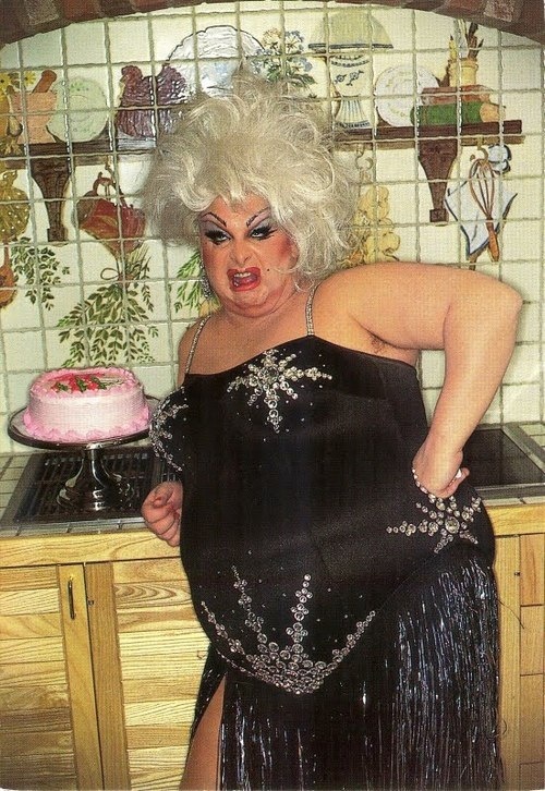 a woman in a black dress standing next to a counter with a cake on it