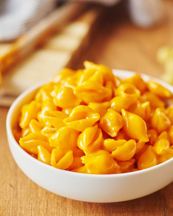 a white bowl filled with macaroni and cheese on top of a wooden table