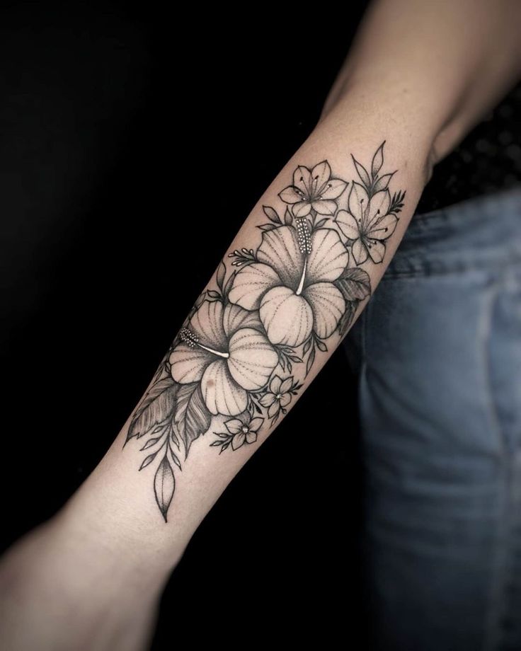 a woman's arm with flowers and leaves tattooed on the left side of her arm