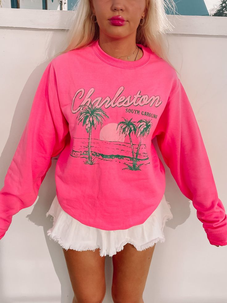 The Charleston Crewneck from Sassy Shortcake is a hot pink preppy sweatshirt. She features a beachy scene with green palm trees and the text "Charleston South Carolina" in white and green. She is soft, lightweight, and absolutely adorable! Oversized fit + unisex sizing. Model is wearing a size small. Pink Casual Sweatshirt For Summer, Summer Pink Crew Neck Sweatshirt, Trendy Spring Beach Sweatshirt, Trendy Sweatshirt For Beach In Spring, Pink Crew Neck Sweatshirt For Summer, Pink Cotton Top With Palm Tree Print, Pink Summer Vacation Sweatshirt, Spring Vacation Sweatshirt, Pink Sweatshirt For Summer Vacation