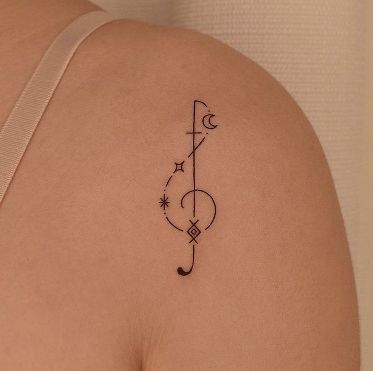 a tattoo on the back of a woman's left shoulder, which has a musical note and stars