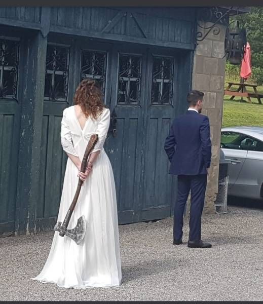 a woman in a white dress is holding a hammer and standing next to a man in a suit