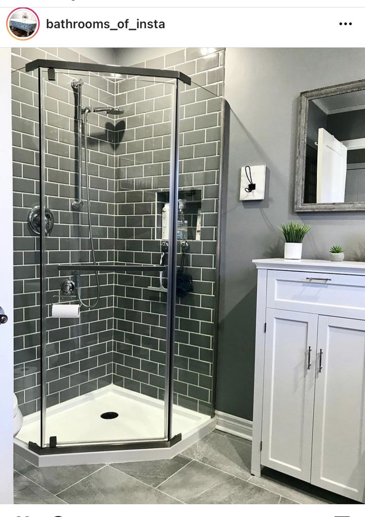 a walk in shower sitting next to a white cabinet and sink on top of a tiled floor