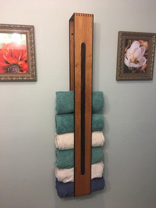 a wooden towel rack in the corner of a bathroom with towels stacked on top of it