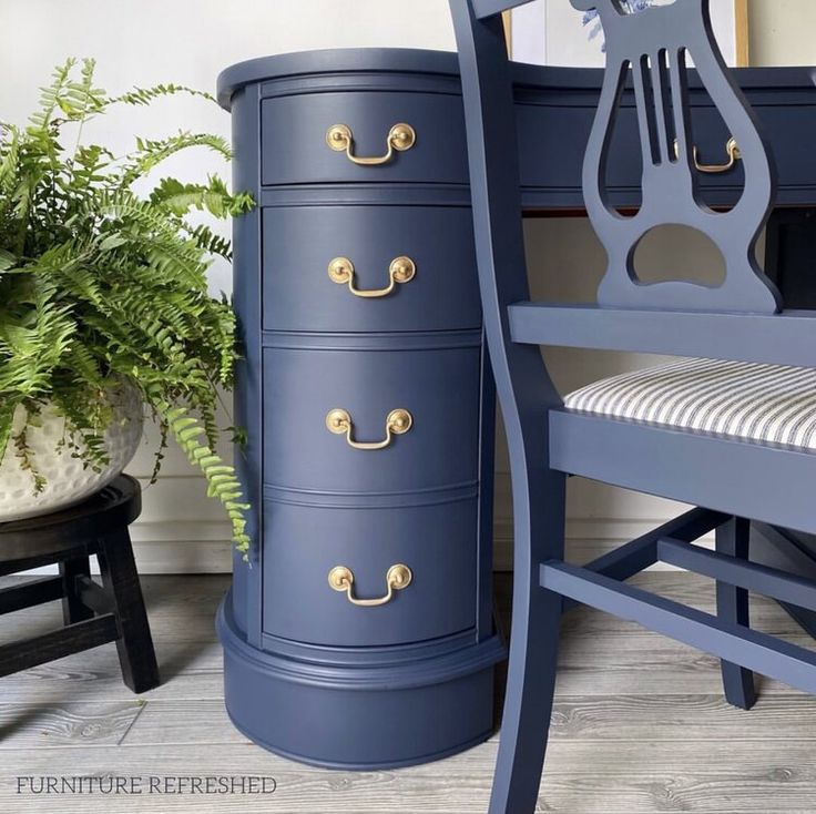 a blue dresser next to a chair and potted plant