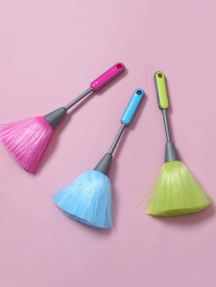 three different colored brushes on a pink background