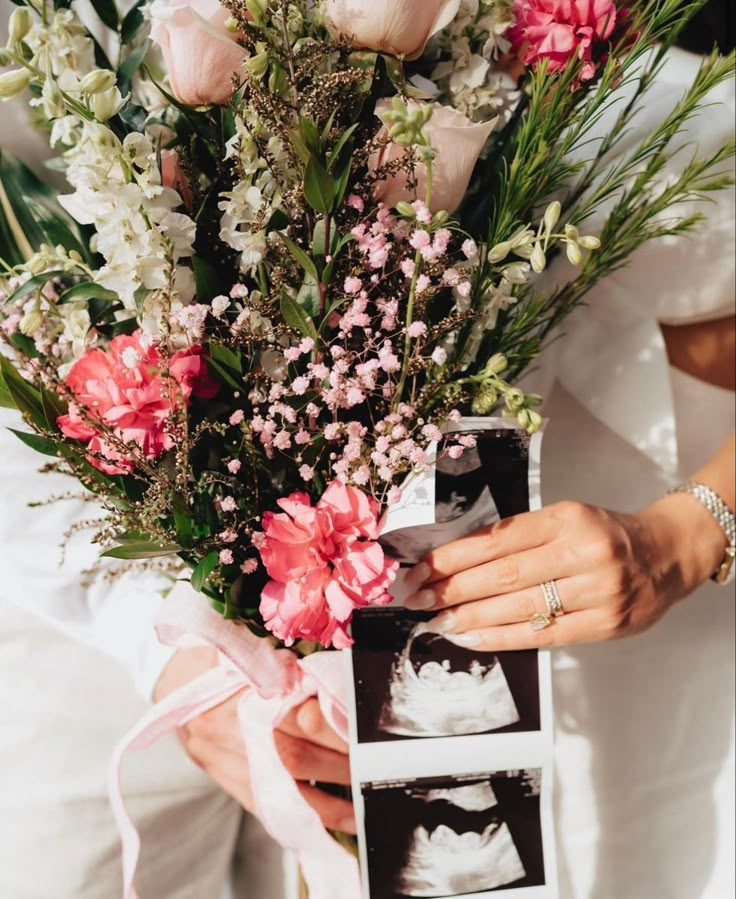 a person holding a bouquet of flowers in their hand and an album on the ground