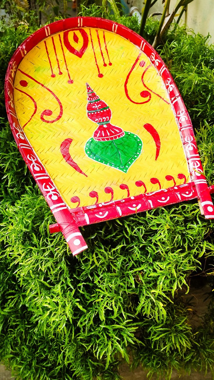 a yellow and red fan sitting on top of green plants