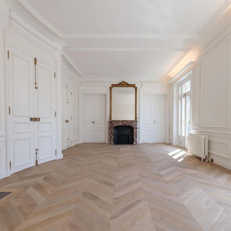 an empty room with white walls and wood floors, large mirror on the wall in the corner