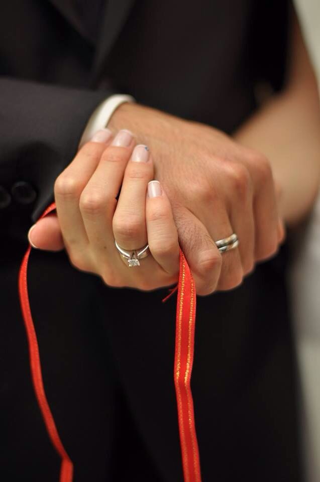 a close up of a person holding onto a red ribbon with two rings on it