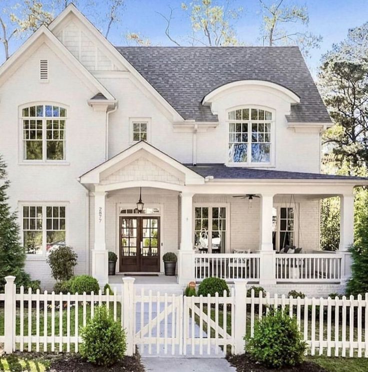 a large white house with two story windows and a black door on the front porch