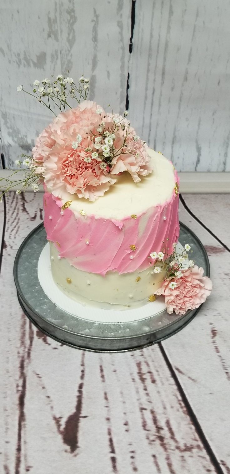 a pink and white cake sitting on top of a wooden table