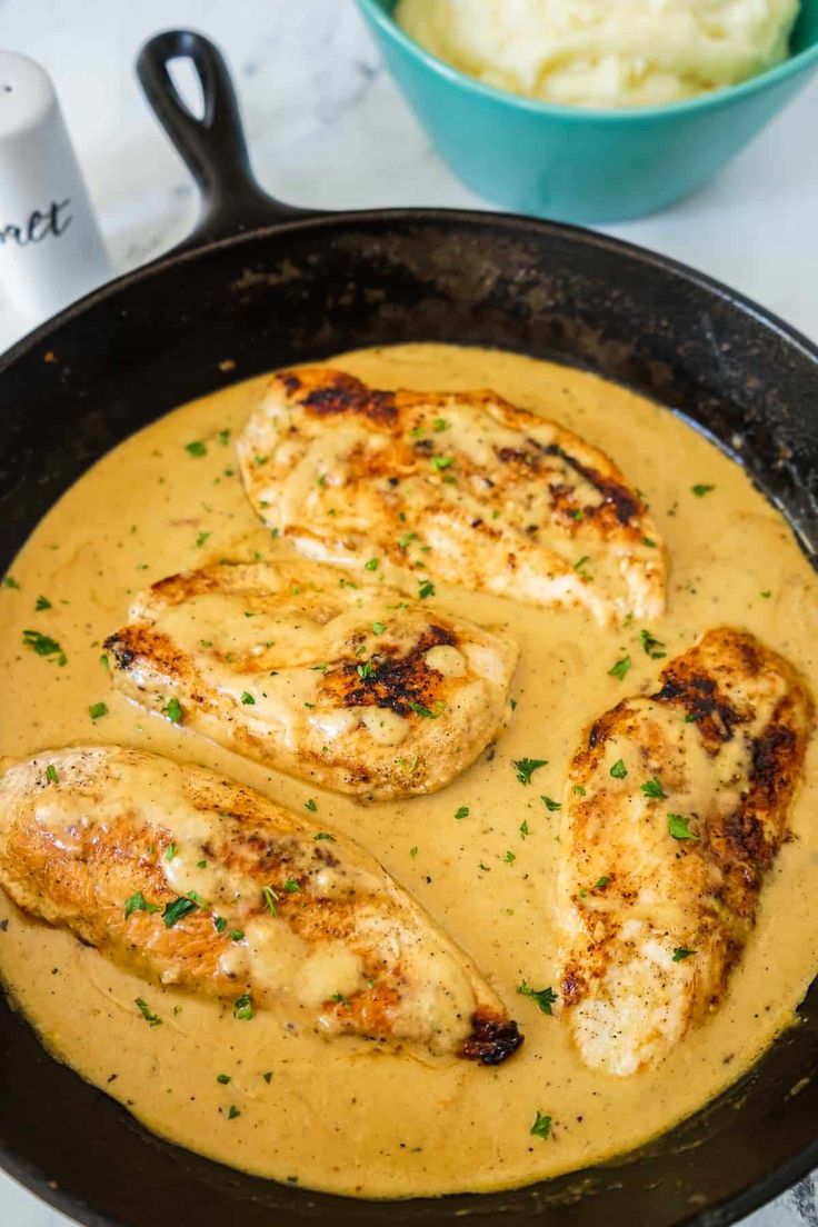 chicken with gravy in a skillet next to mashed potatoes