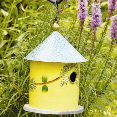 a yellow birdhouse hanging from a tree branch