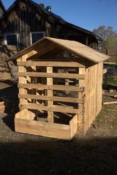 an outhouse made from wooden pallets in front of a barn