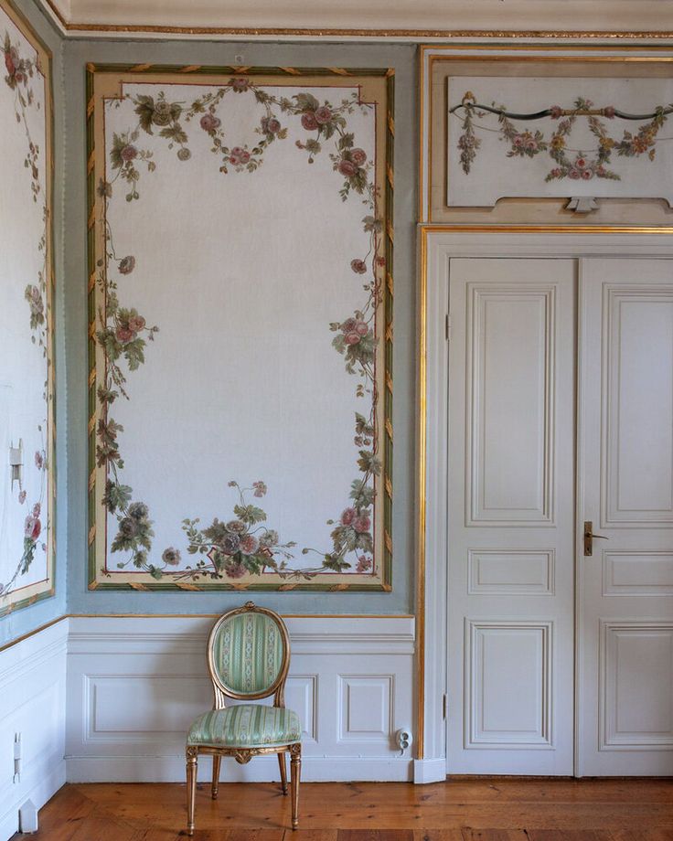 a chair sitting in front of a painting on the wall next to a doorway and door