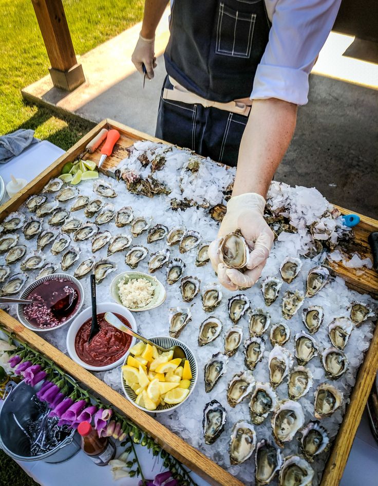 a person in an apron is placing oysters on a table with other foods and condiments