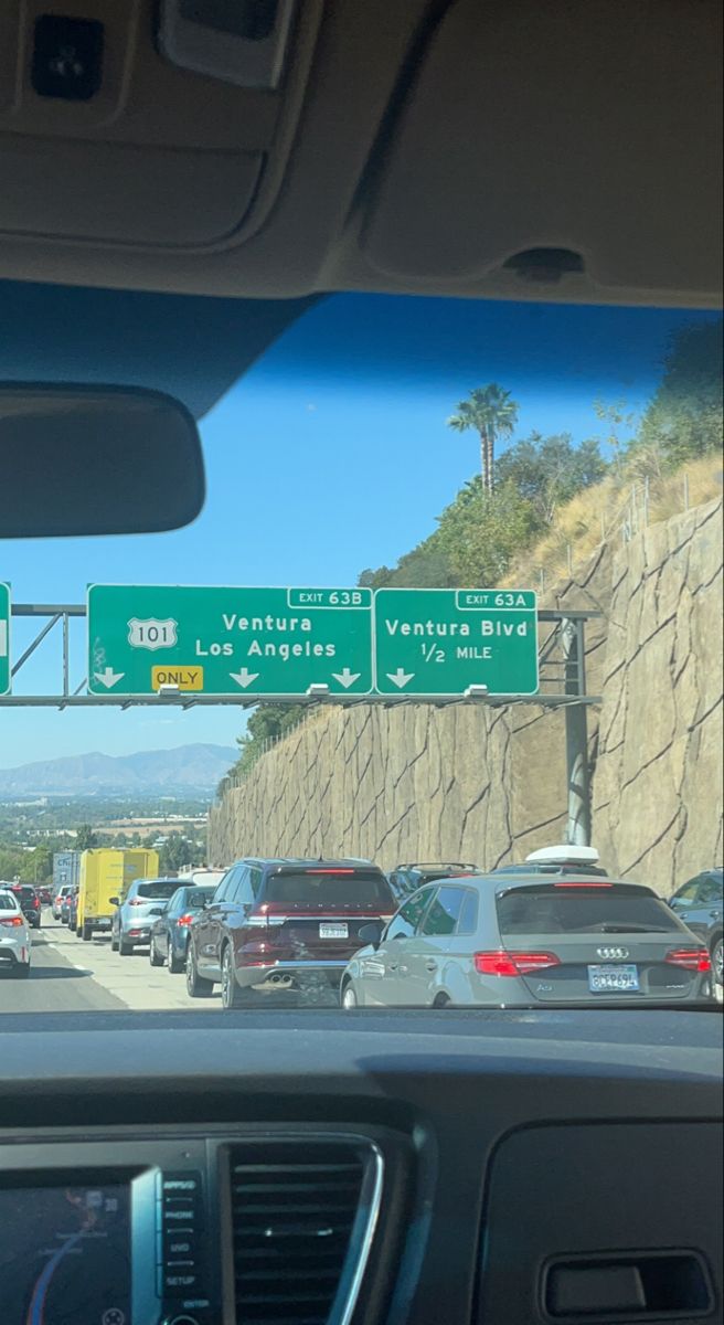 the view from inside a car looking at street signs and cars driving down the road