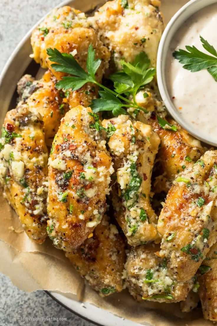 a white plate topped with chicken wings and ranch dressing