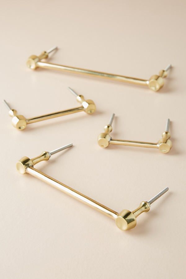 four pairs of gold nose studs on a white surface with one pair missing from the top