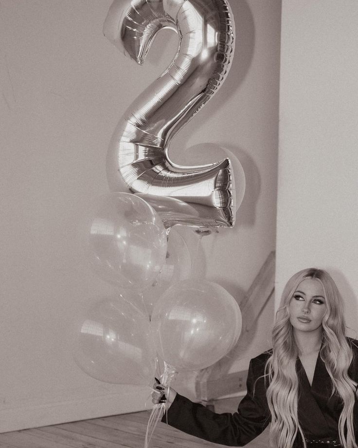 a woman sitting on the floor with balloons in front of her and number 2 balloon