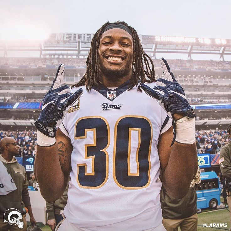 a man with dreadlocks standing in front of a crowd at a football game