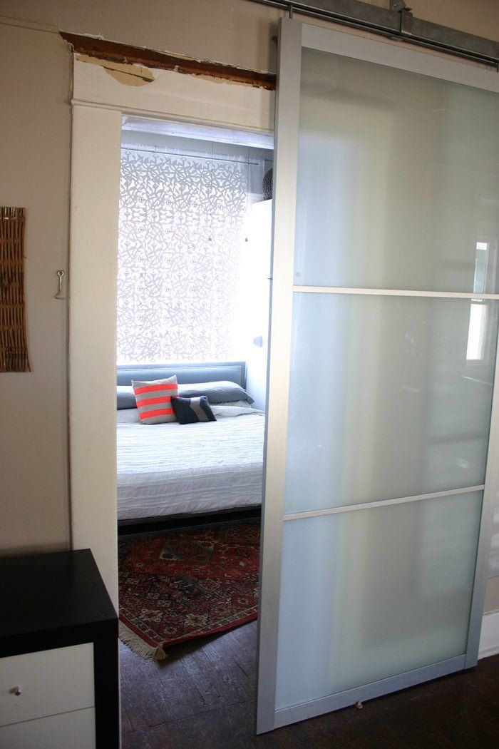 the sliding glass door is open to reveal a bedroom with a bed in the background