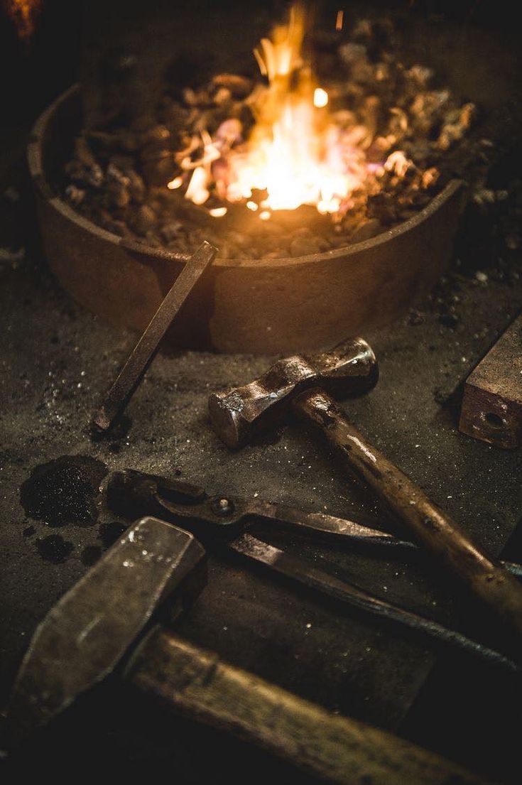 there are many tools on the table next to the campfire that is lit up