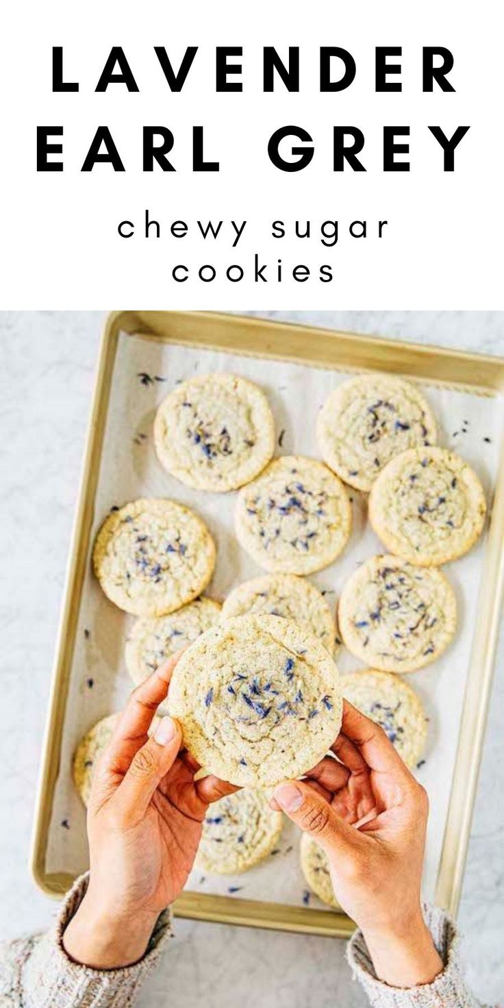 a person holding a cookie in front of some cookies on a tray with text overlay that reads lavender ear grey chewy sugar cookies