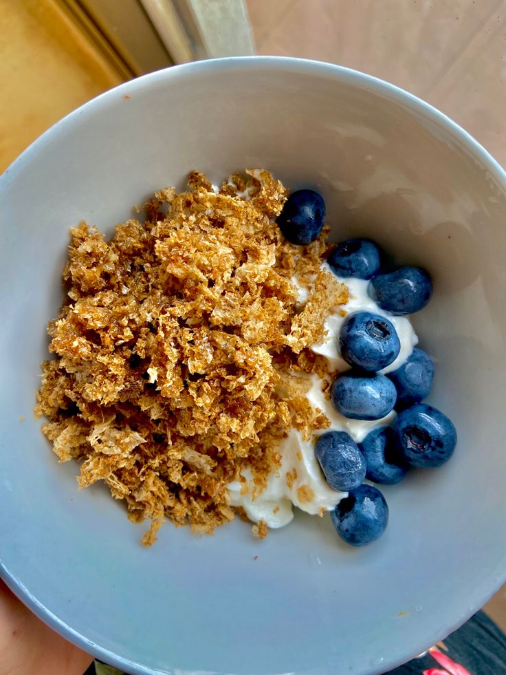 blueberries and yogurt in a white bowl with crumbs on top