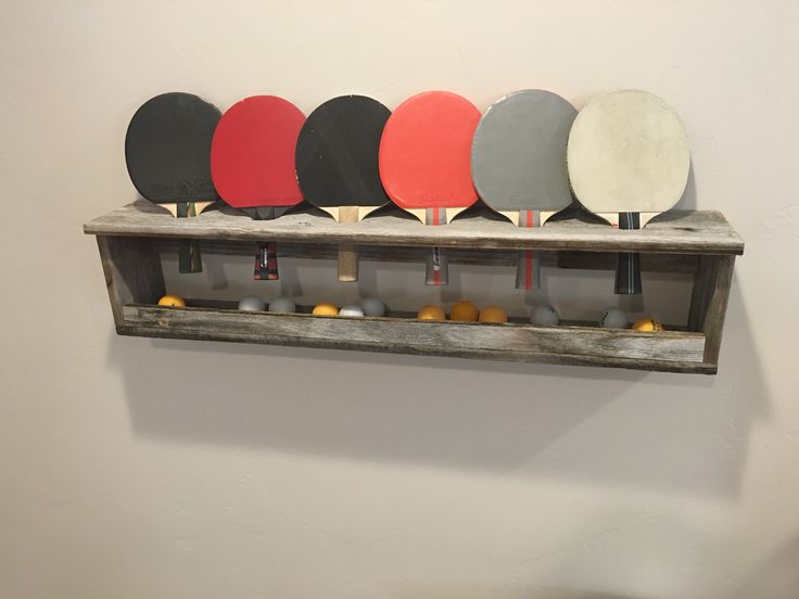 ping pong paddles are lined up on a shelf in front of a wall