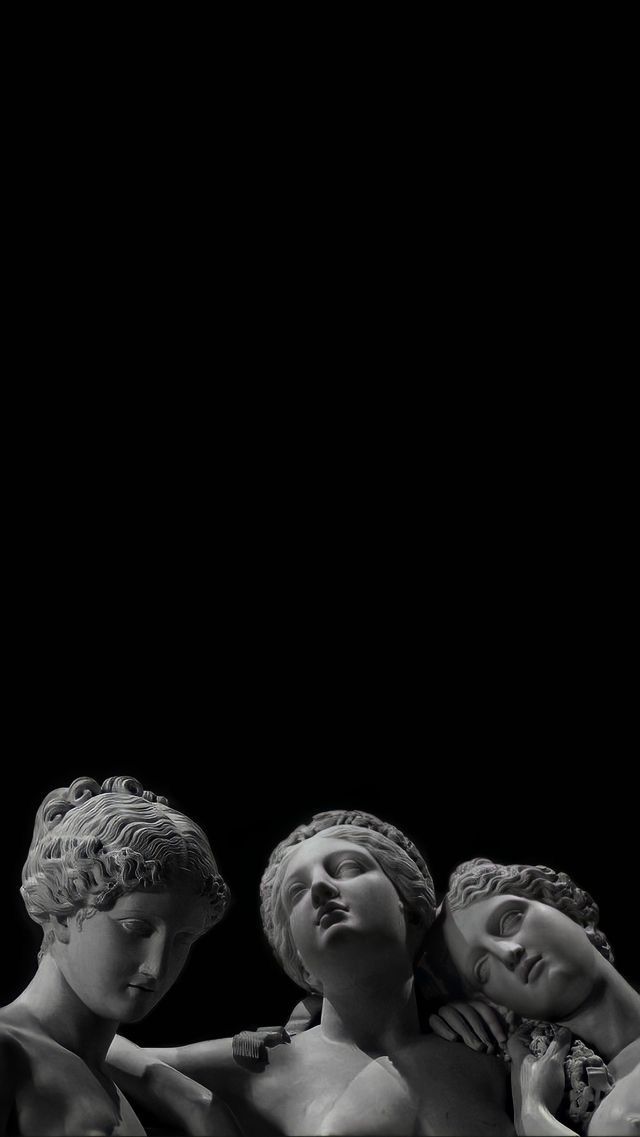 black and white photograph of three statues in front of a dark background, with one holding the other's head