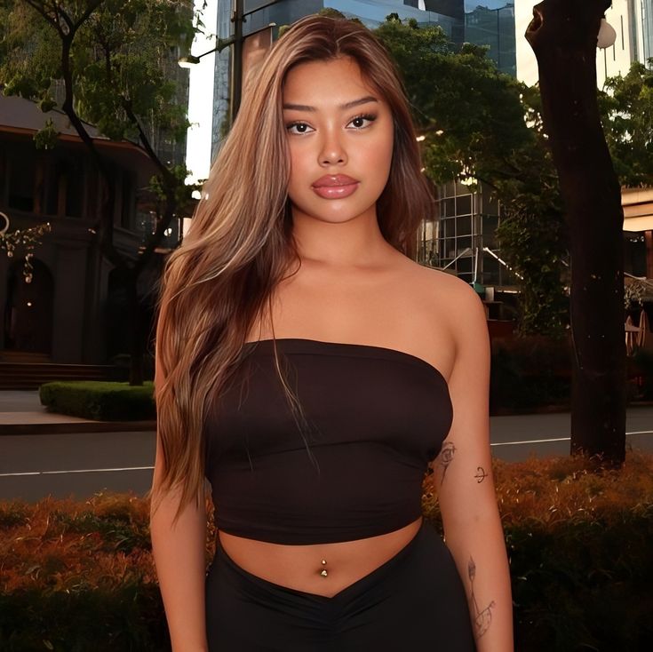 a woman with long hair in a black top and skirt posing for the camera on a city street