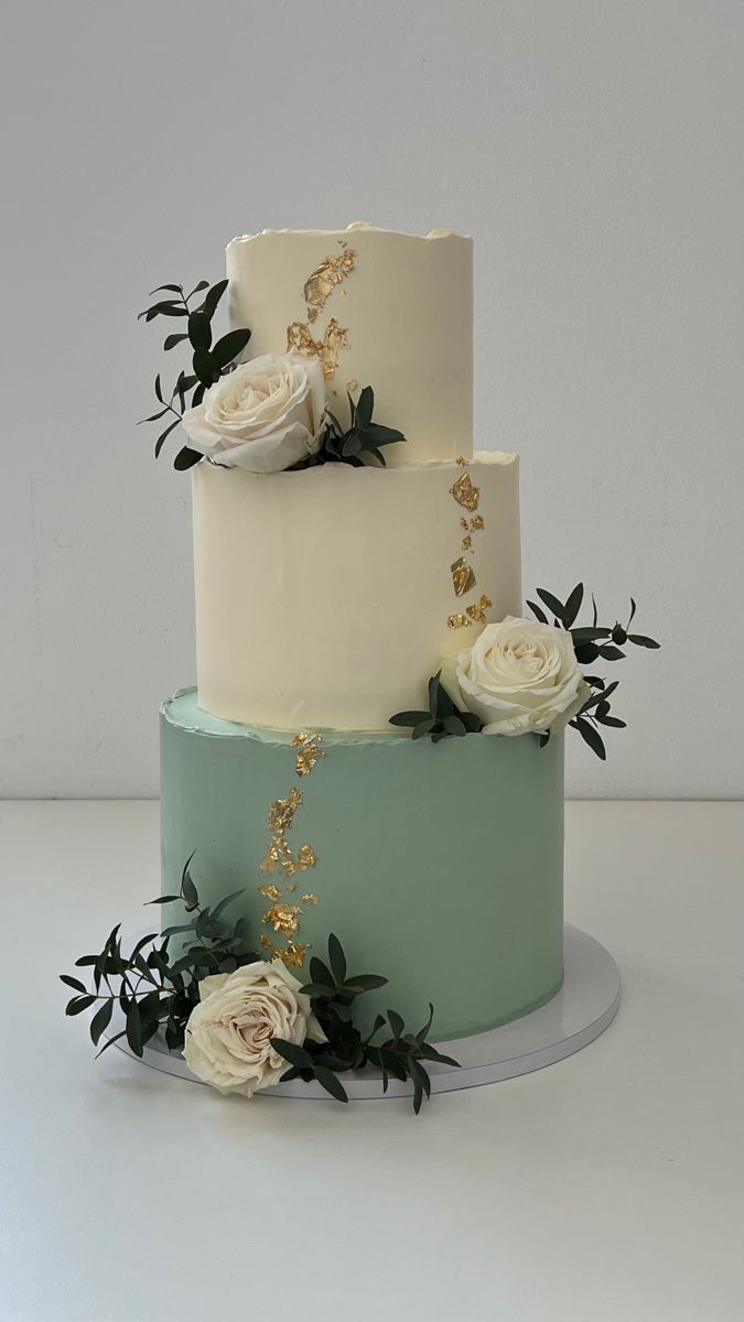 a three tiered cake with white flowers and greenery